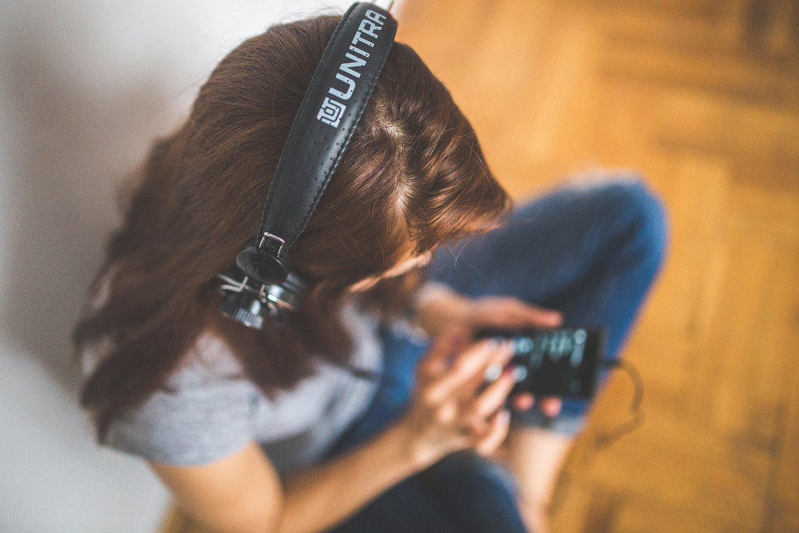 Woman with headphones put on and playing music on phone